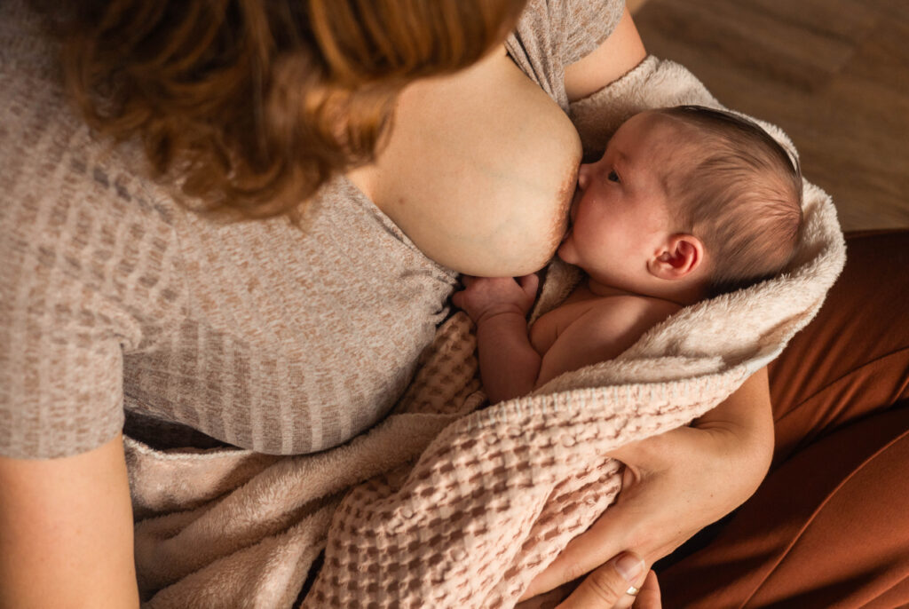 Een moeder geeft borstvoeding aan haar baby, van bovenaf gefotografeert tijdens newbornshoot