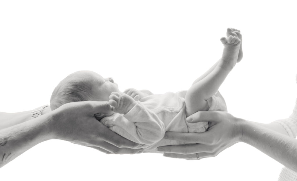 De ouders houden hun handen aan beide kanten van de baby.
