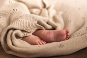 Kleine blote babyvoetjes steken uit een dekentje.