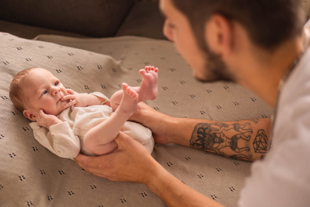 Newborn baby ligt op een dekentje te kijken naar zijn papa