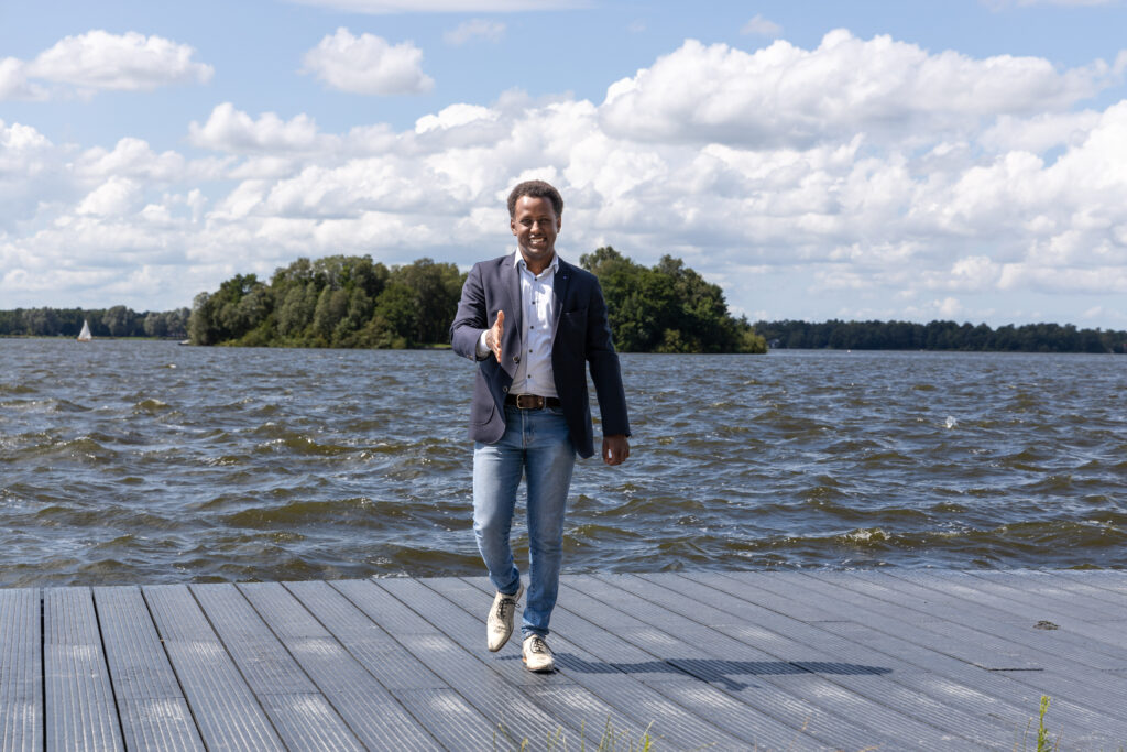 Abush heet jou welkom voor zijn bedrijf, hij staat uitnodigend op deze foto en steekt zijn hand uit.