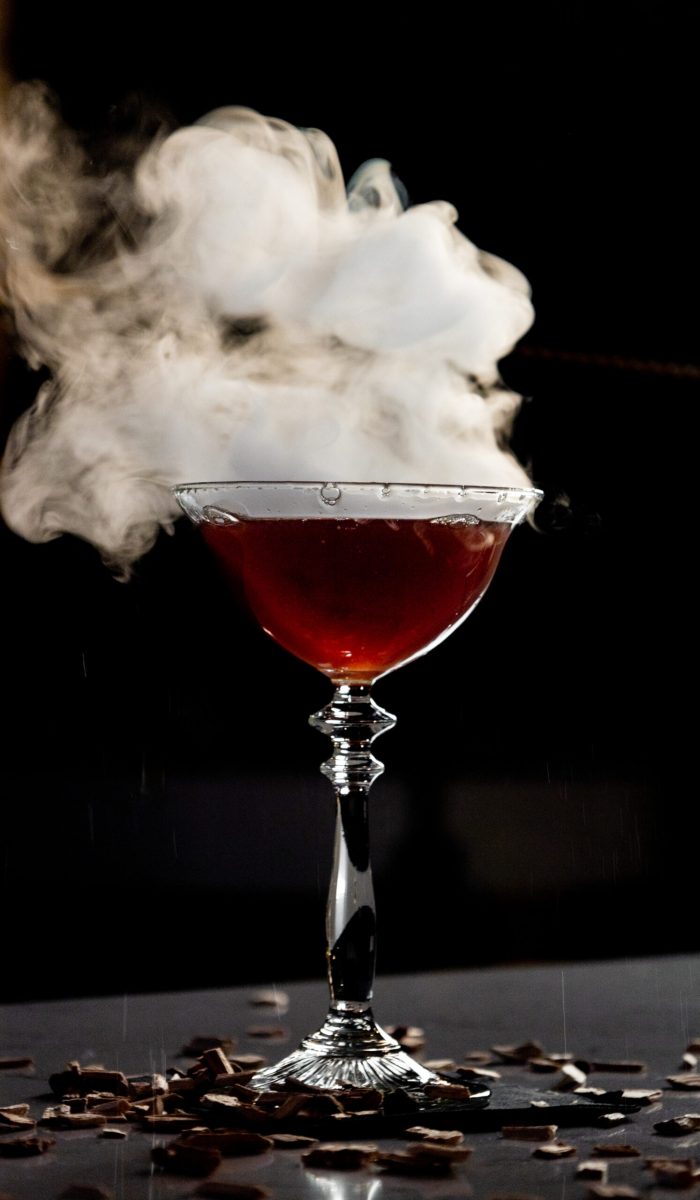 Een cocktail staat op de bar en er komt allemaal rook af.